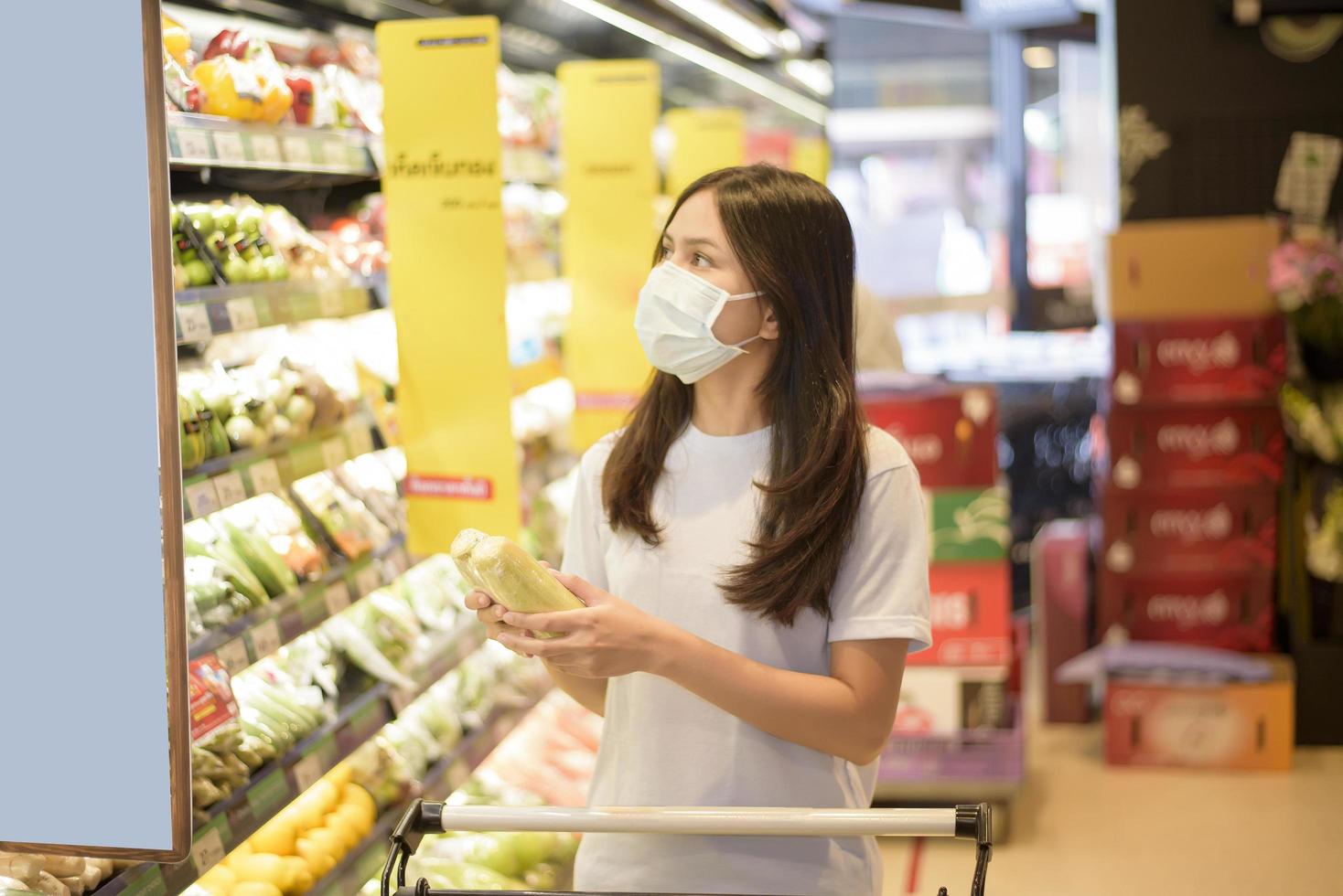 Frau kauft im Supermarkt mit Gesichtsmaske ein foto