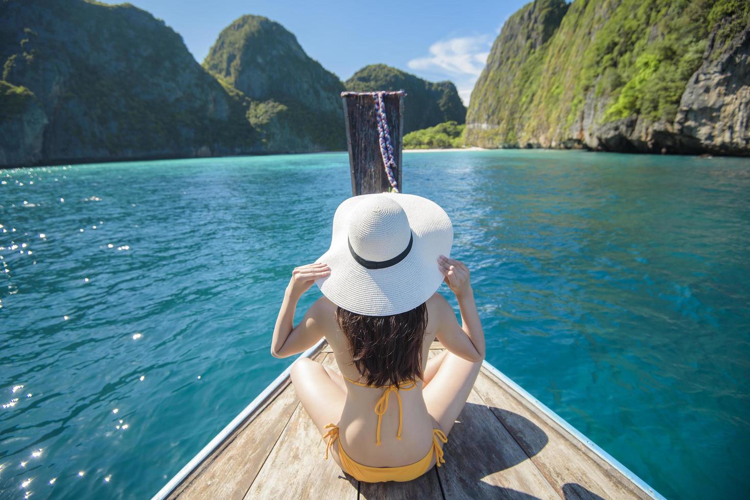 Blick auf eine Frau im Badeanzug, die auf einem traditionellen thailändischen Longtail-Boot über schöne Berge und das Meer, die Phi-Phi-Inseln, thailand, genießt foto