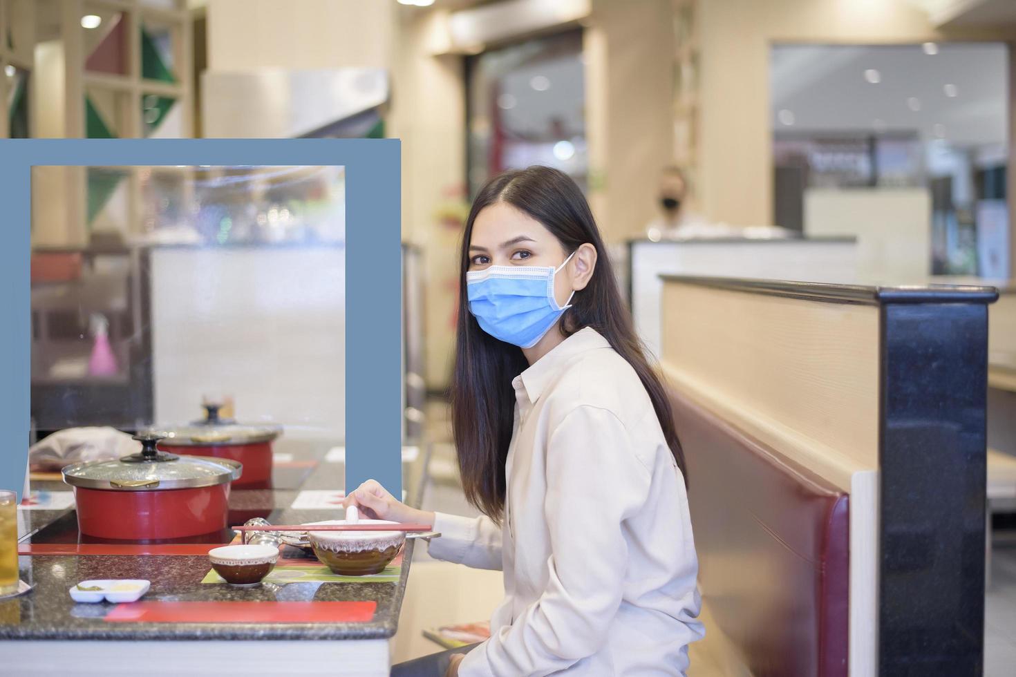 Frau isst im Restaurant mit Protokoll zur sozialen Distanzierung, während sie die Stadt aufgrund einer Coronavirus-Pandemie sperrt foto