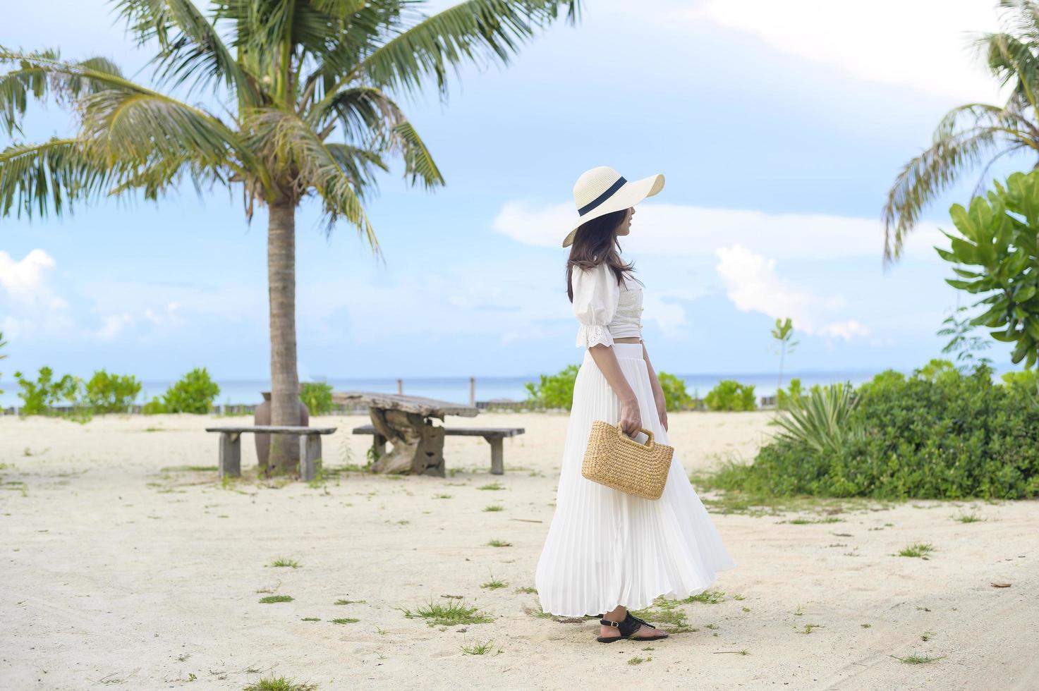 eine glückliche schöne Frau im weißen Kleid, die am Strand, im Sommer und im Ferienkonzept genießt und sich entspannt foto