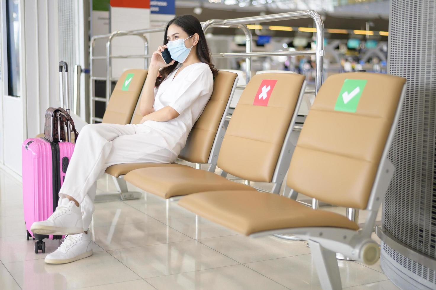 Eine reisende Frau trägt eine Schutzmaske auf dem internationalen Flughafen, reist unter der Covid-19-Pandemie, Sicherheitsreisen, Protokoll zur sozialen Distanzierung, neues normales Reisekonzept foto