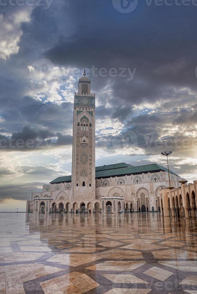 Flachwinkelansicht der historischen Moschee Hasan II mit dem höchsten Minarett gegen dramatischen Himmel foto
