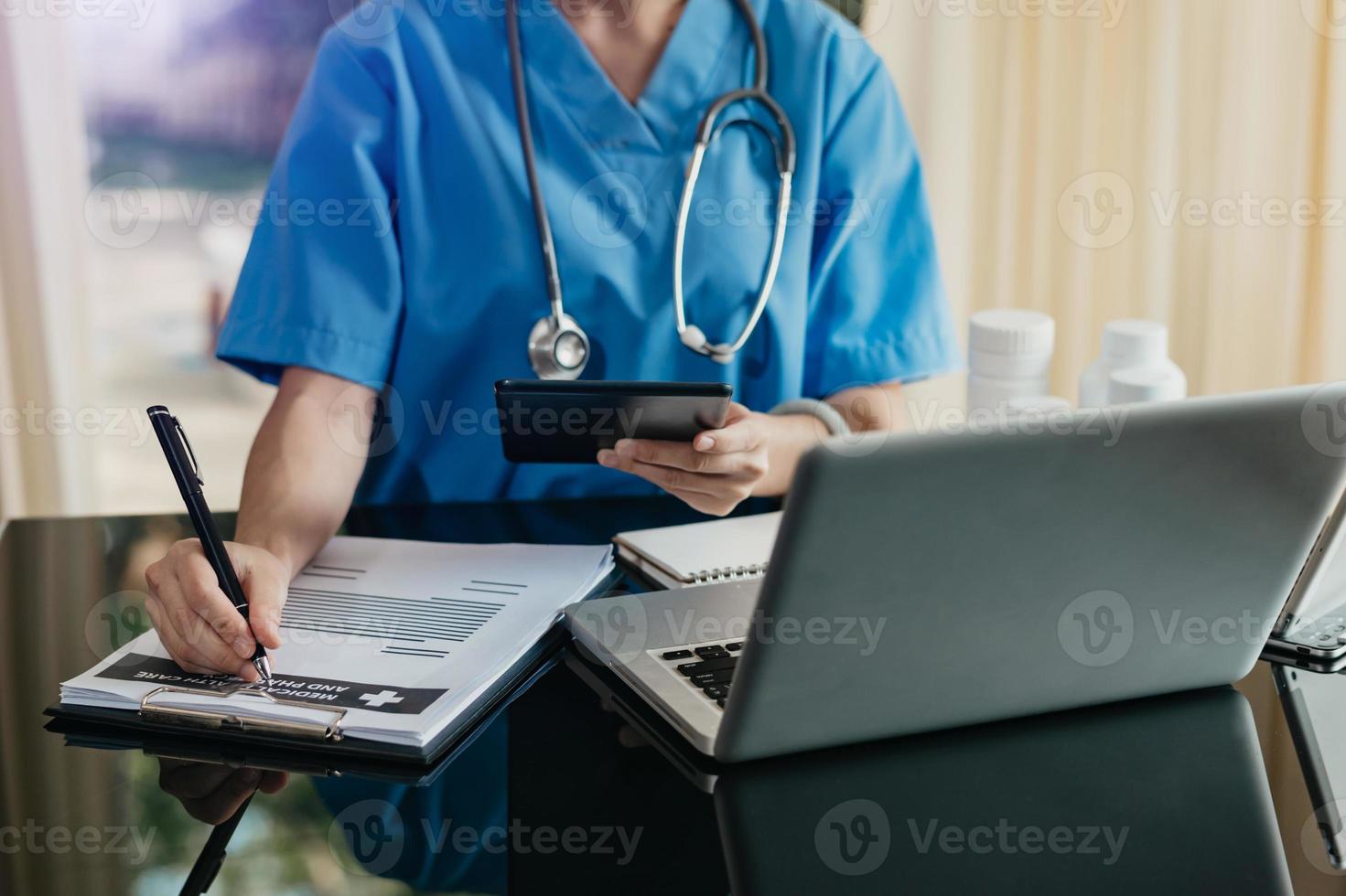 Medizintechnik-Konzept. Arzt, der mit Handy und Stethoskop und digitalem Tablet-Laptop in einem modernen Büro im Krankenhaus arbeitet foto