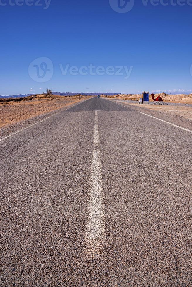 gerade Asphaltstraße mit Markierungen durch die Wüste gegen den Himmel foto