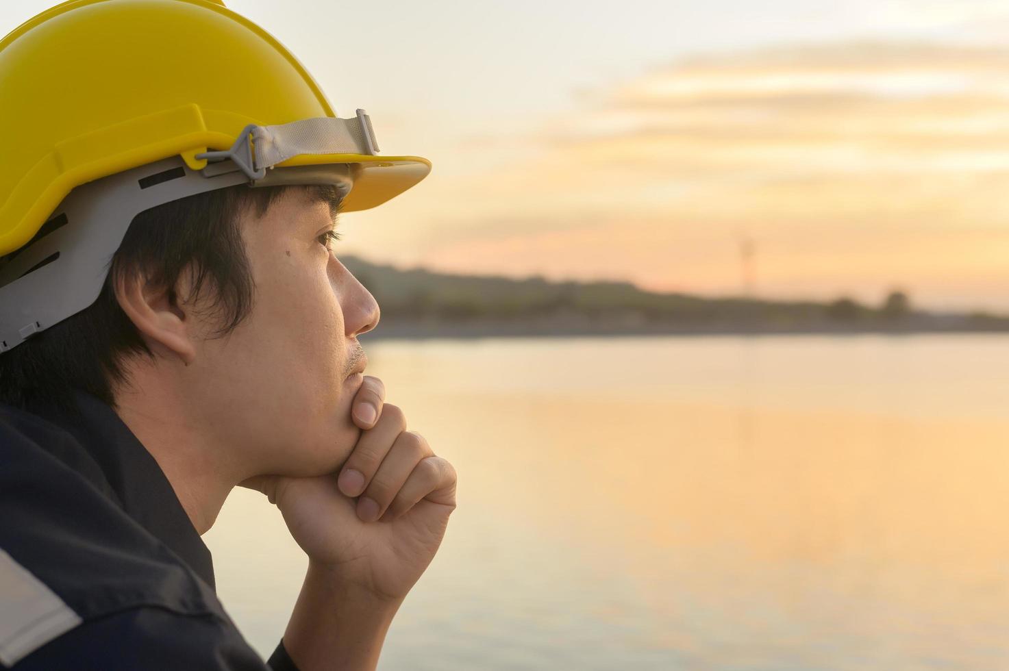 ein männlicher Ingenieur, der bei Sonnenuntergang einen Schutzhelm trägt. foto