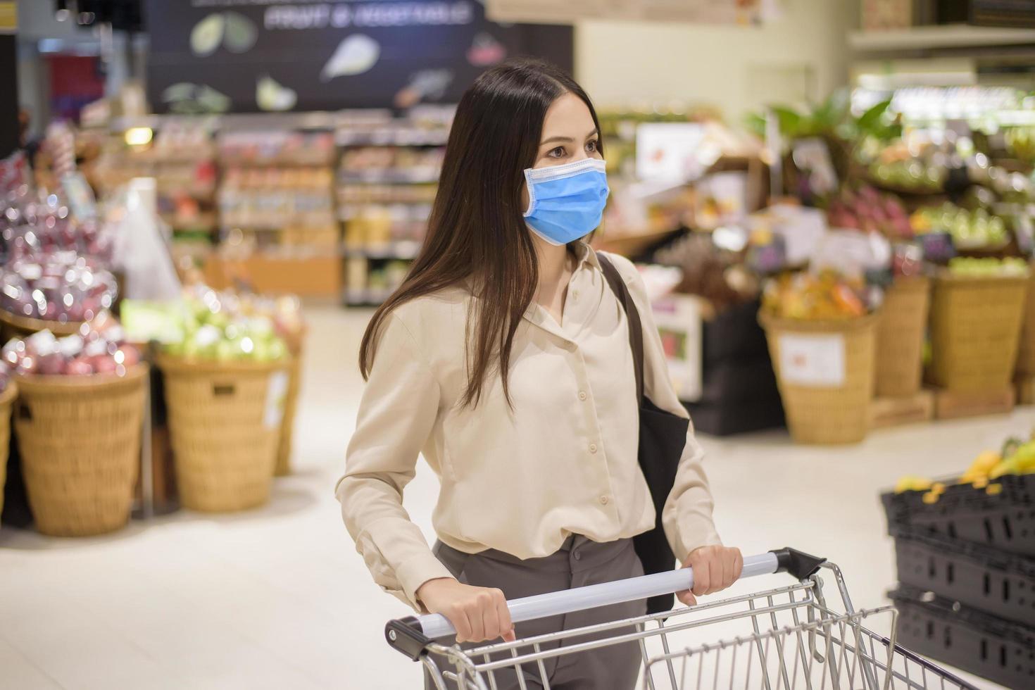 Frau kauft im Supermarkt mit Gesichtsmaske ein foto