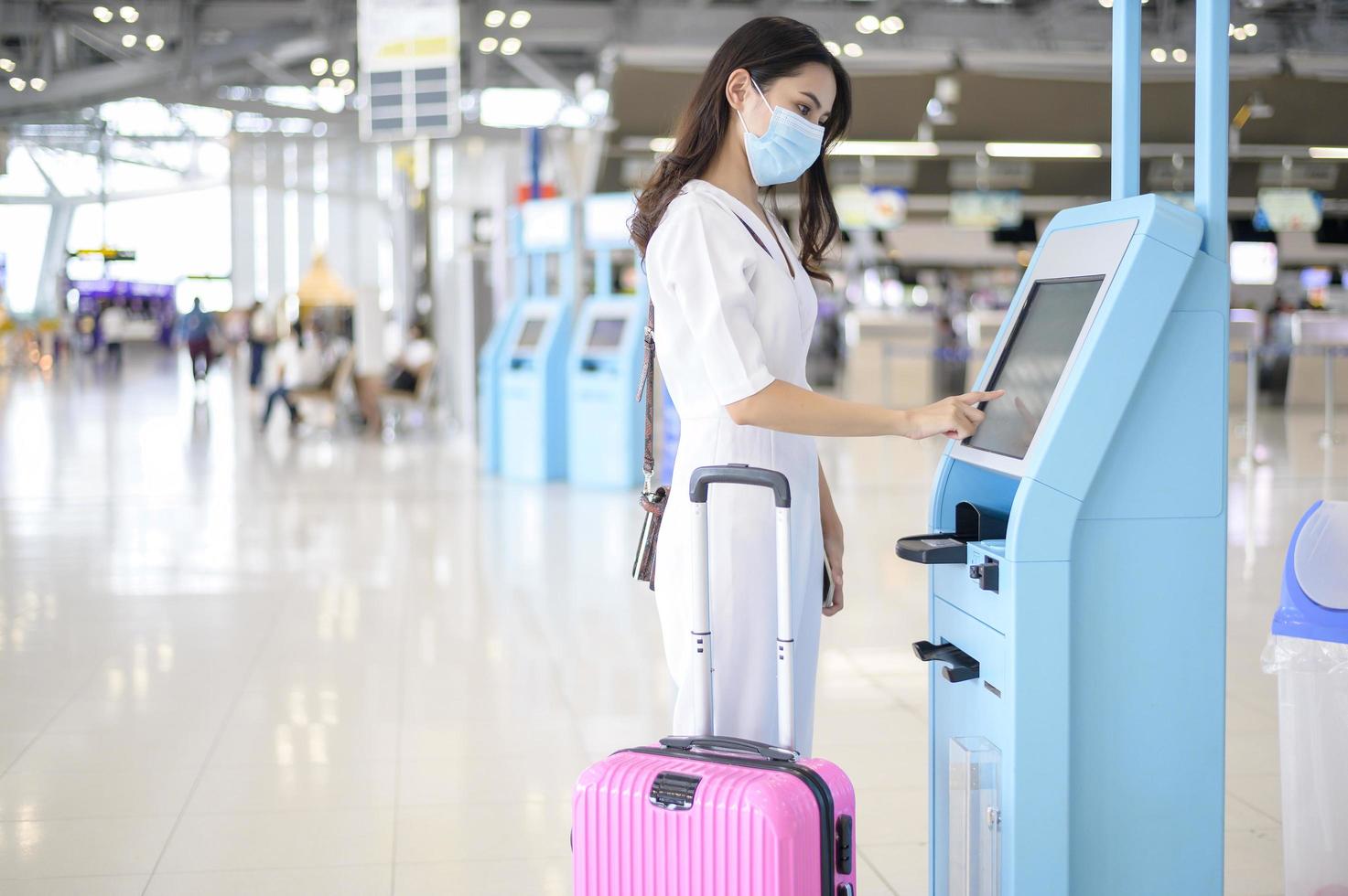 Eine reisende Frau trägt eine Schutzmaske auf dem internationalen Flughafen, reist unter der Covid-19-Pandemie, Sicherheitsreisen, Protokoll zur sozialen Distanzierung, neues normales Reisekonzept foto