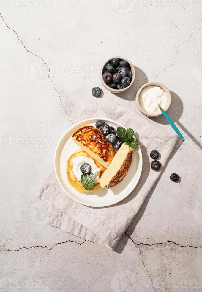 Hüttenkäsepfannkuchen serviert mit Quark und Blaubeeren, Draufsicht flach auf Marmorhintergrund foto