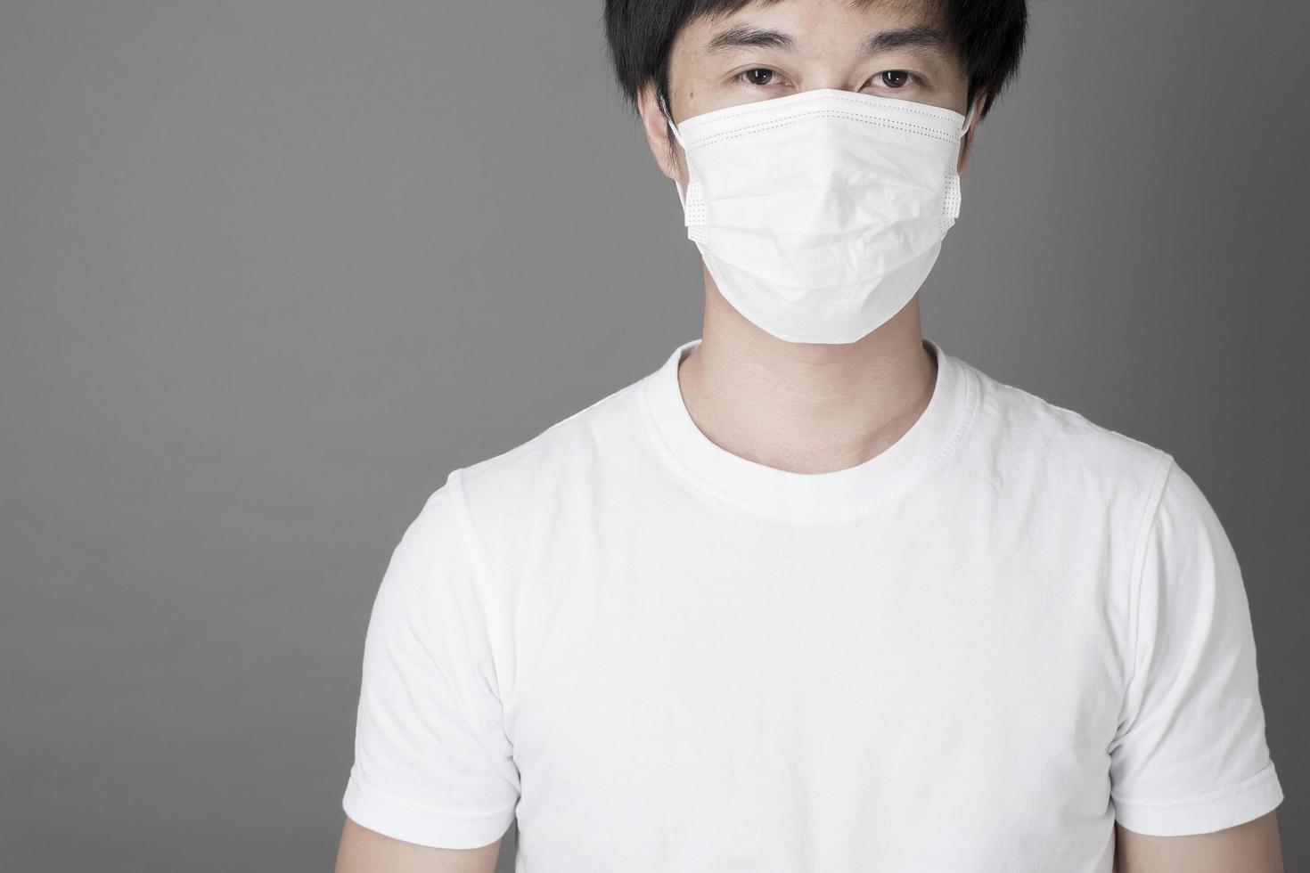 Porträt des Mannes mit chirurgischer Maske im Studio, Gesundheitskonzept foto