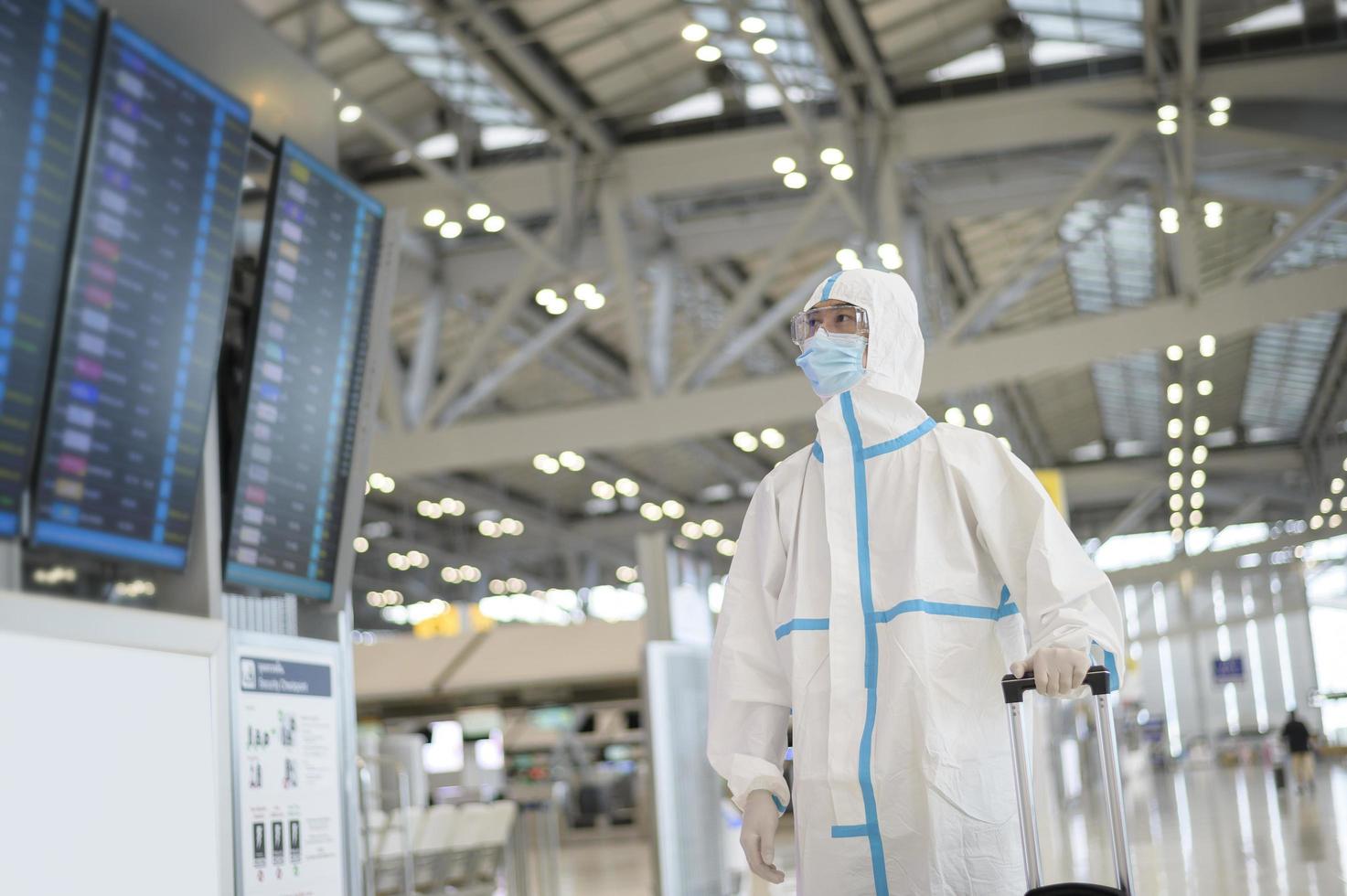 Ein asiatischer Mann trägt einen PSA-Anzug auf dem internationalen Flughafen, Sicherheitsreisen, Covid-19-Schutz, Konzept der sozialen Distanzierung foto