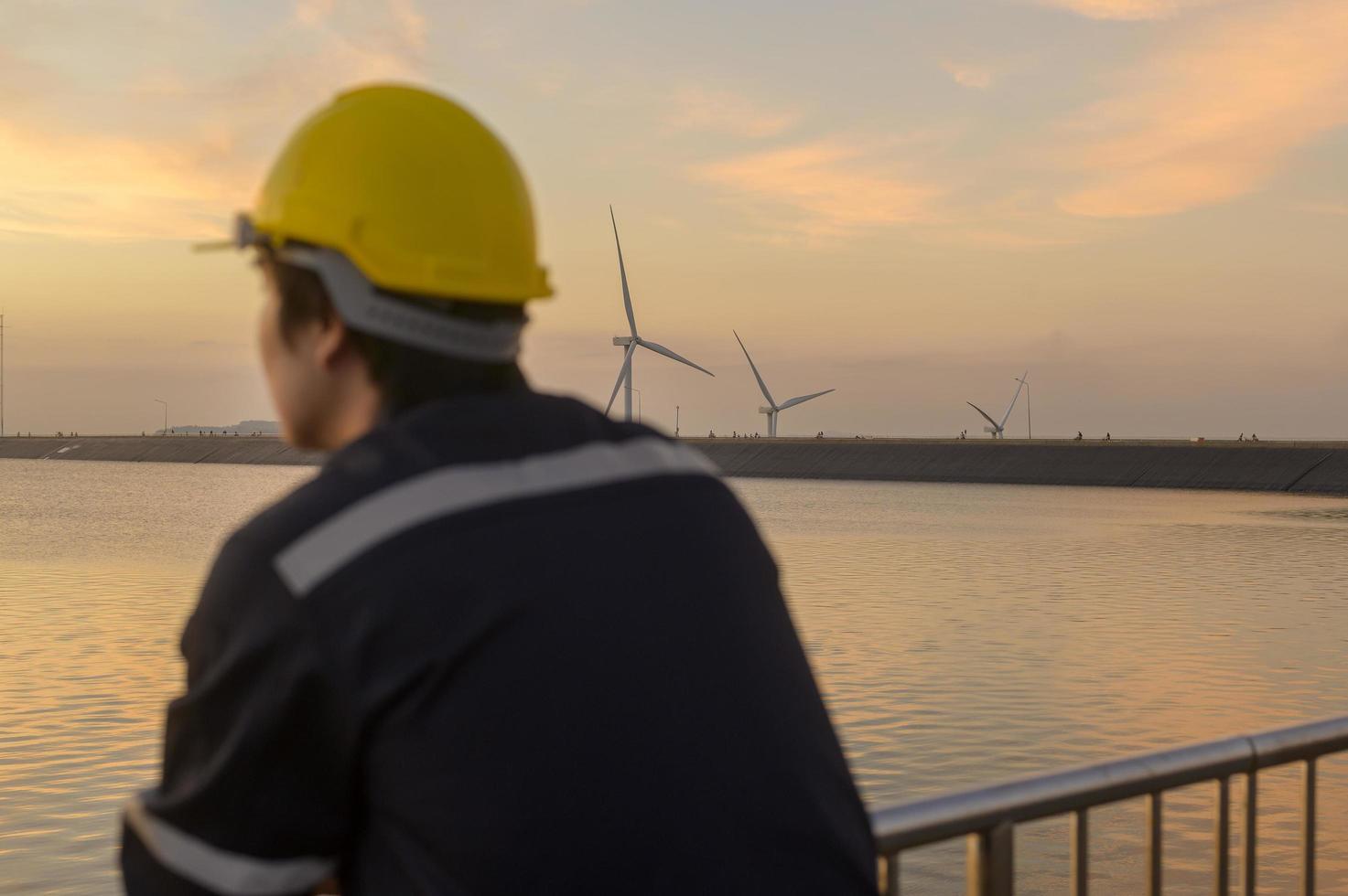 ein männlicher Ingenieur, der bei Sonnenuntergang einen Schutzhelm trägt, selektiver Fokus auf den Hintergrund foto