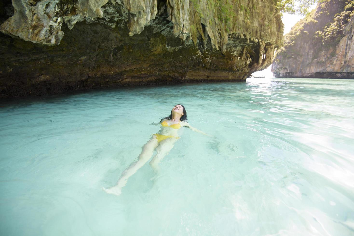 Fröhliche schöne Frau im gelben Badeanzug, die das klare Meer, das Sommer- und Urlaubskonzept genießt und entspannt foto