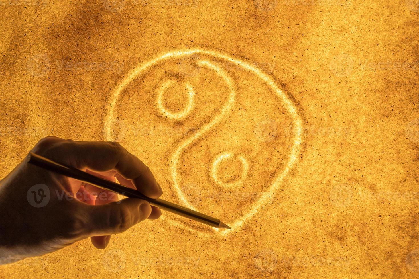 Männerhände zeichnen ein Symbol für Yin Yang in den Sand. das Konzept der Harmonie foto