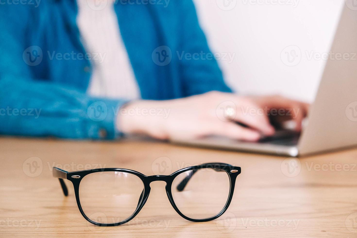 Brillen auf dem Schreibtisch mit Laptop am Arbeitsplatz foto