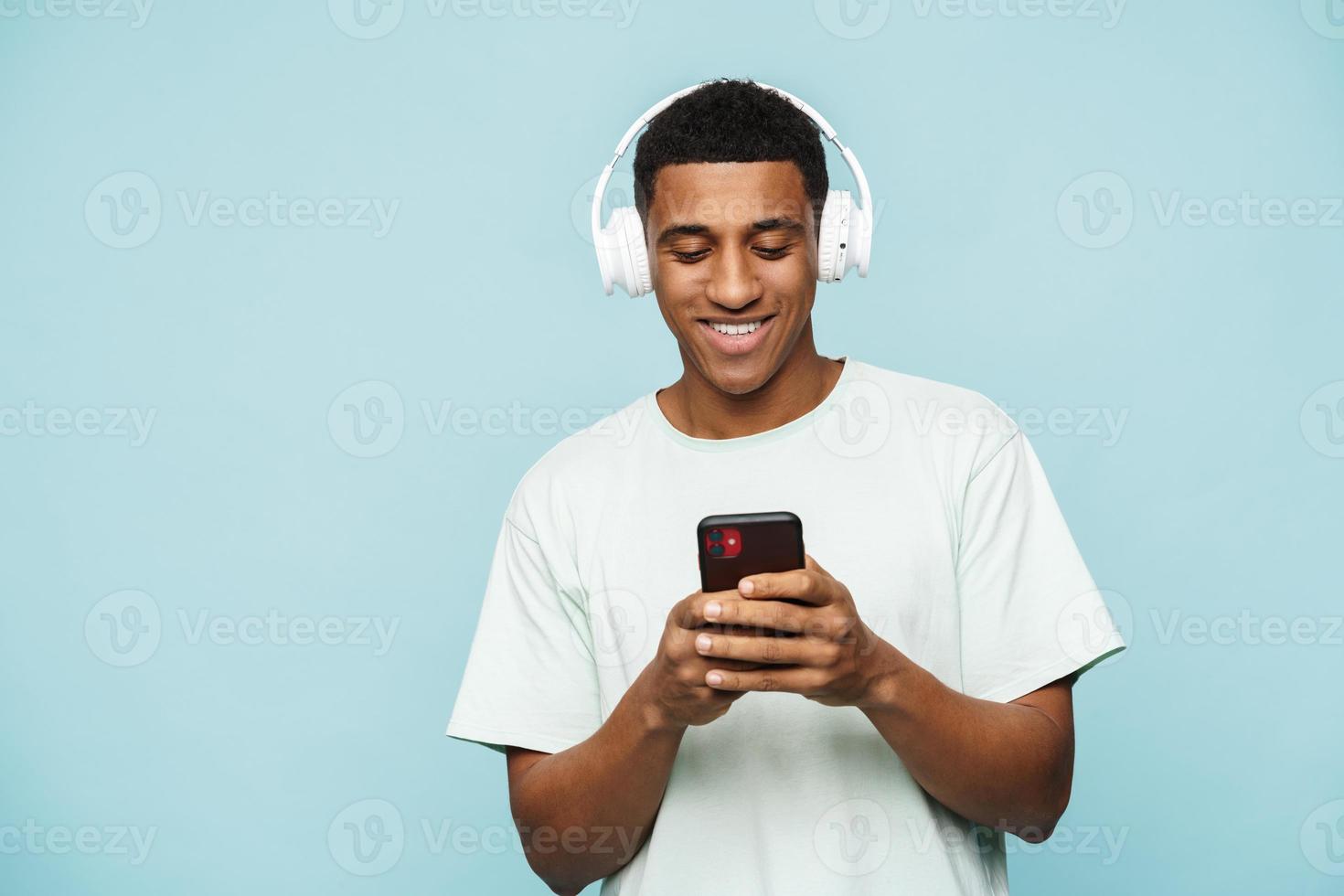 lächelnder afrikanischer mann, der mit kopfhörern telefonisch tippt foto