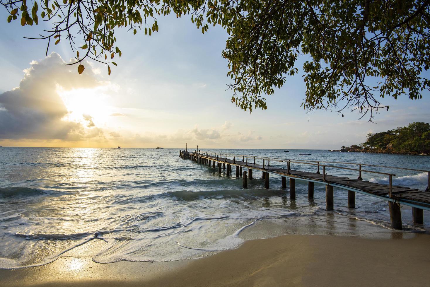 erstaunlicher sandiger tropischer strand mit silhouette holzbrücke aus dem strand heraus tropisch - promenade oder holzsteg zum horizont am meer ozean paradies landschaft , sonnenaufgang oder sonnenuntergang meer dramatischer himmel foto