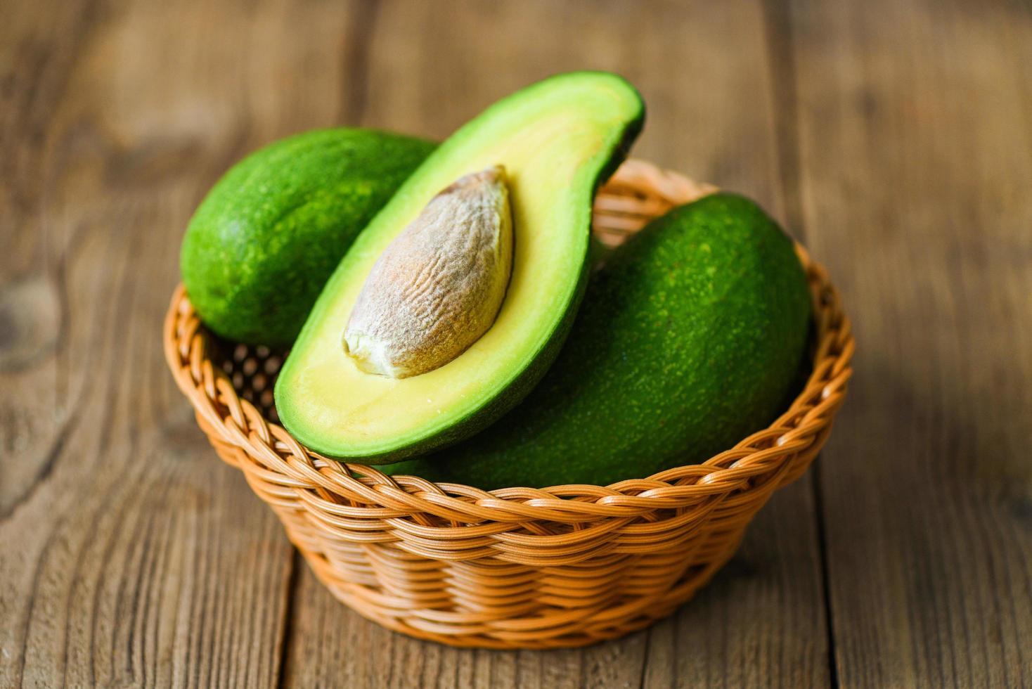 Avocado halbiert im Korb auf dem Holztisch - Obst gesundes Ernährungskonzept foto