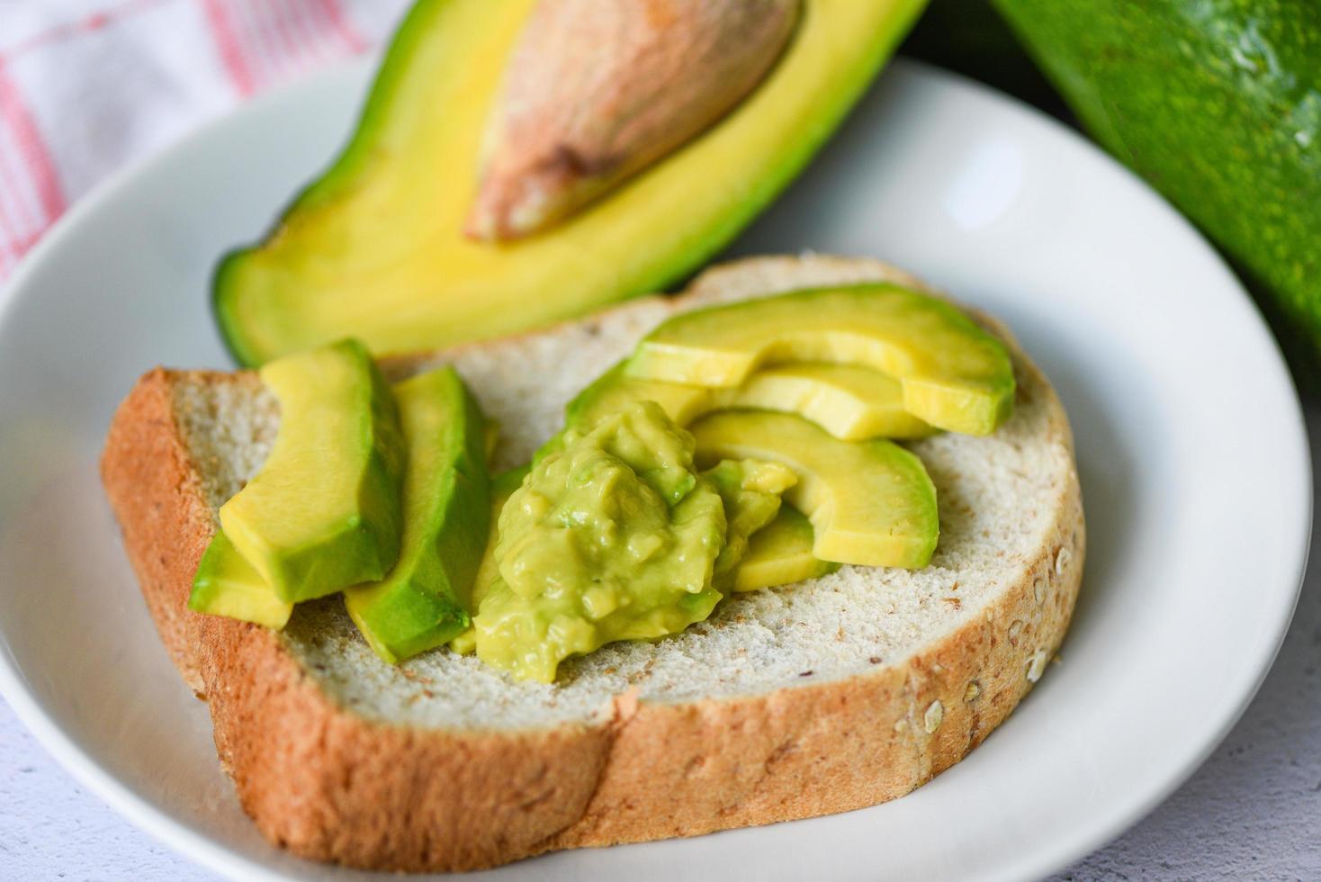 Avocado in Scheiben geschnitten und Avocado-Toast auf weißem Teller Hintergrund Früchte gesunde Ernährung Konzept - Avocado-Dip püriert foto