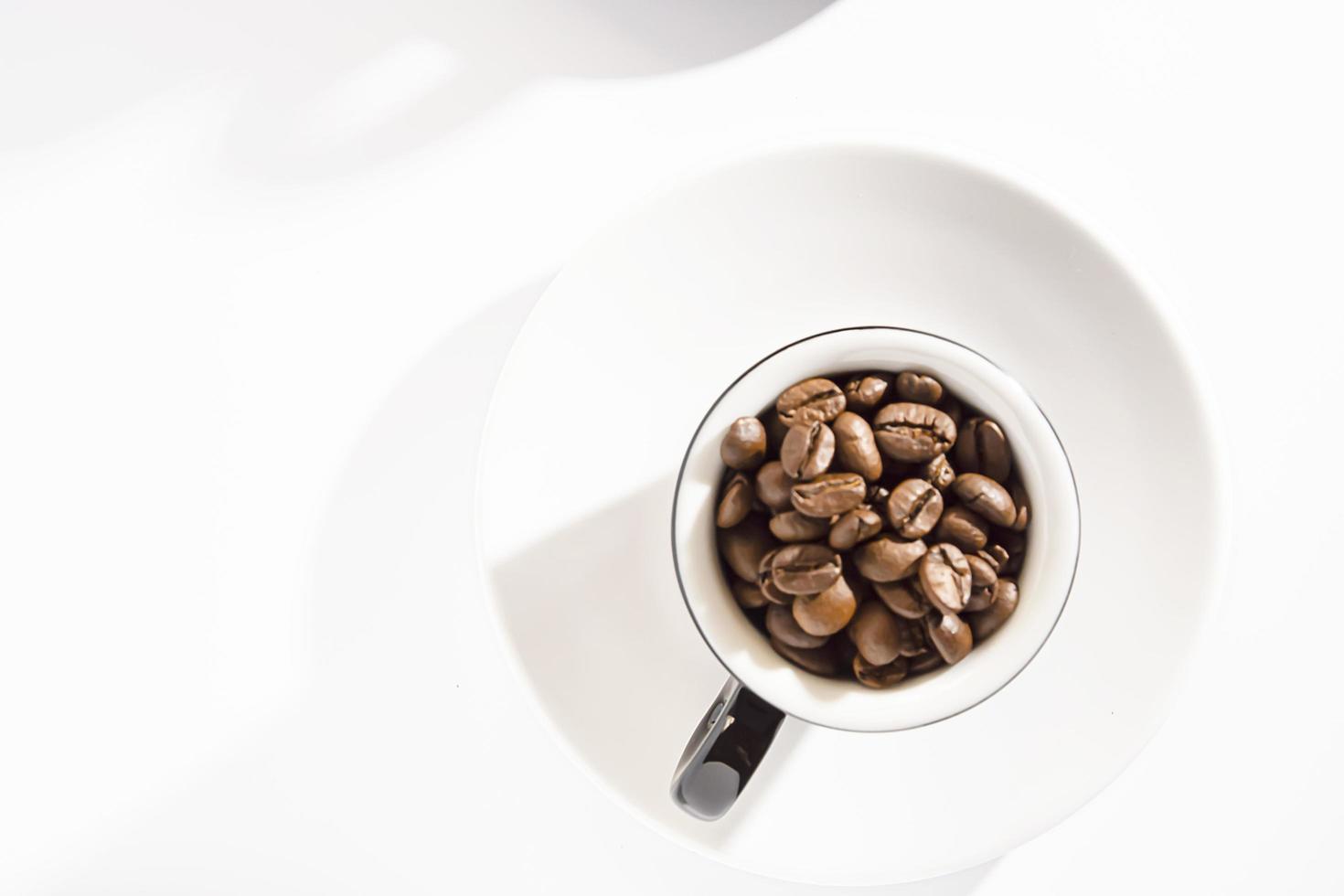 Schwarze Espressotasse mit Kaffeebohnen auf Untertassen auf weißem Hintergrund. Lebensstil. Ihren eigenen Raum. flach. foto