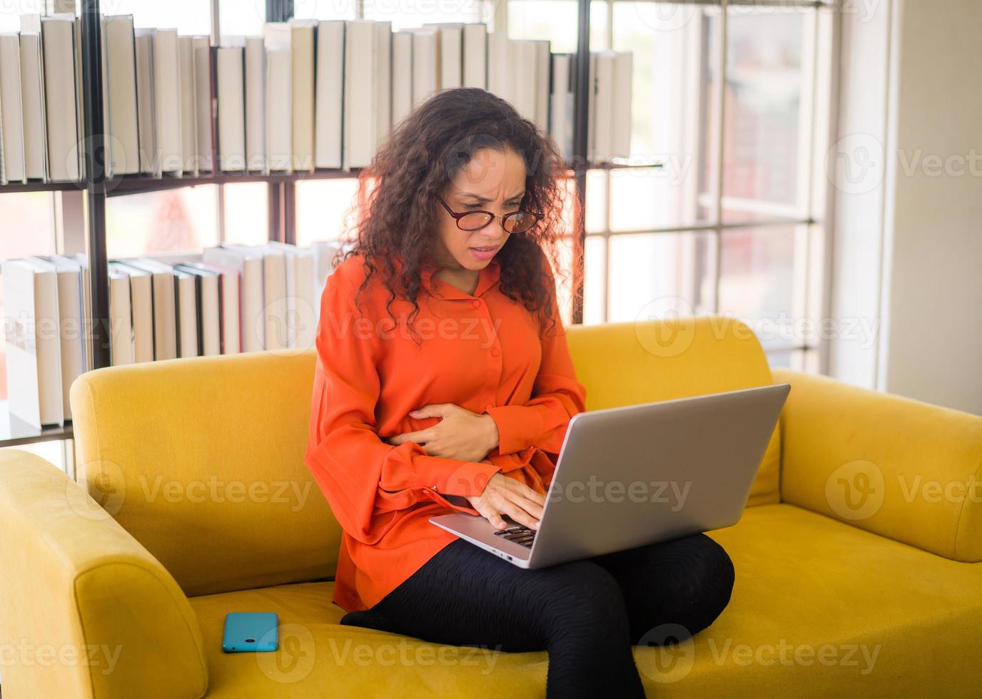 lateinische frau, die mit laptop auf sofa mit müdem gefühl arbeitet foto