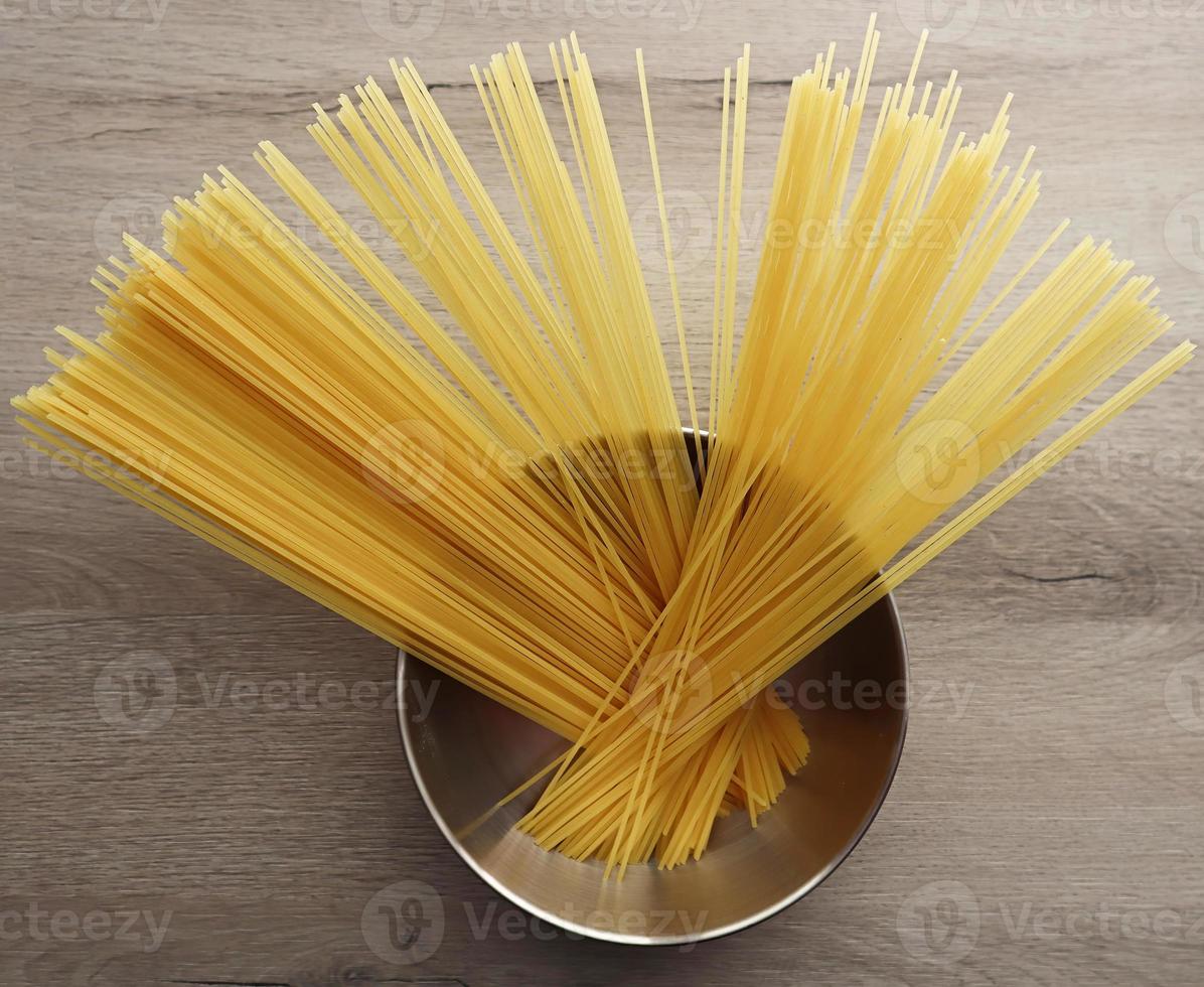 rohe italienische spaghetti in einer schüssel auf hölzernem hintergrund foto