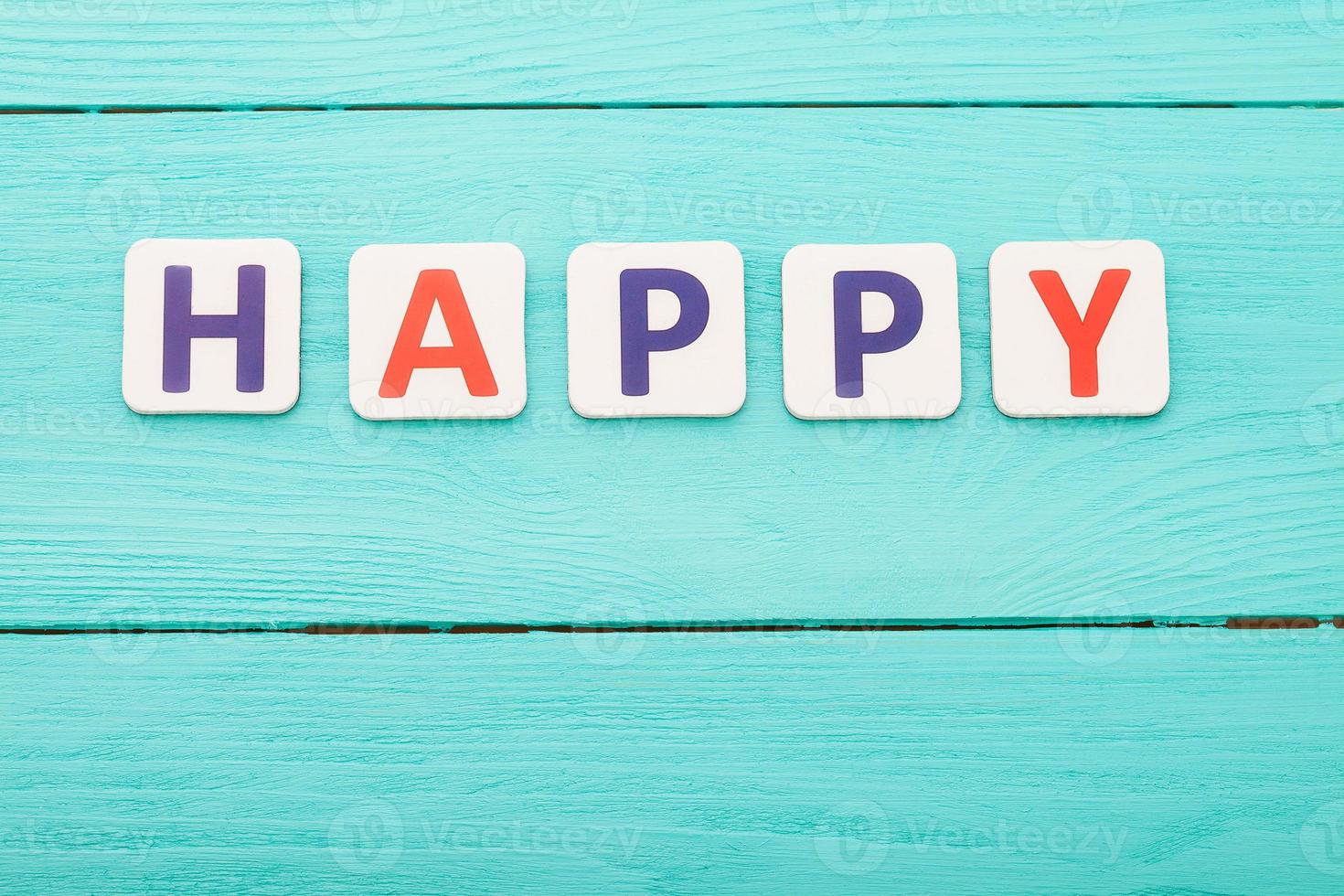 Wort glücklich auf blauem Hintergrund aus Holz. glückliches Gefühlskonzept. Glück. Draufsicht, Kopierbereich foto