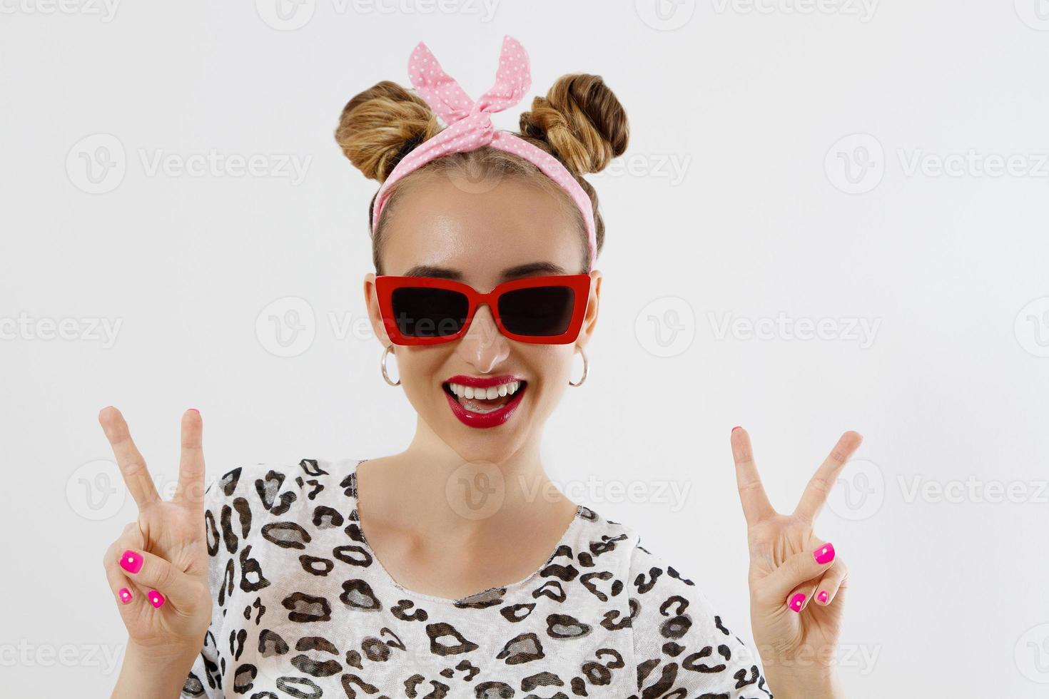 Nahaufnahme Mode Frau Porträt isoliert auf weißem Hintergrund. glückliches Mädchengesicht mit Sonnenbrille. Friedenszeichen. erstaunliche und aufgeregte frau mit lustiger frisur. selektiver Fokus foto