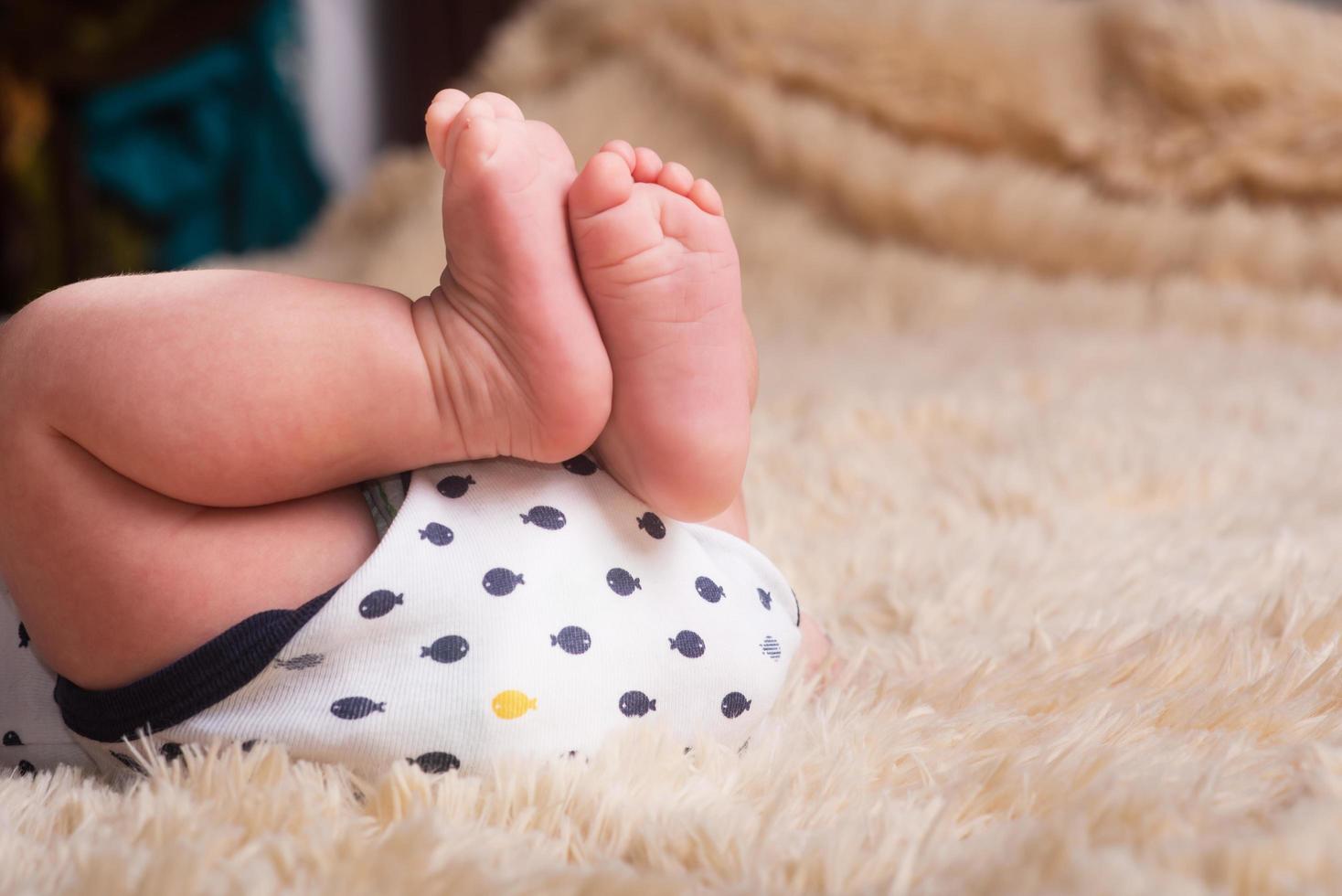 nackte Beine eines Neugeborenen auf einer flauschigen, leichten, tonnenschweren, warmen Decke. süße neugeborene Babyfüße hautnah foto