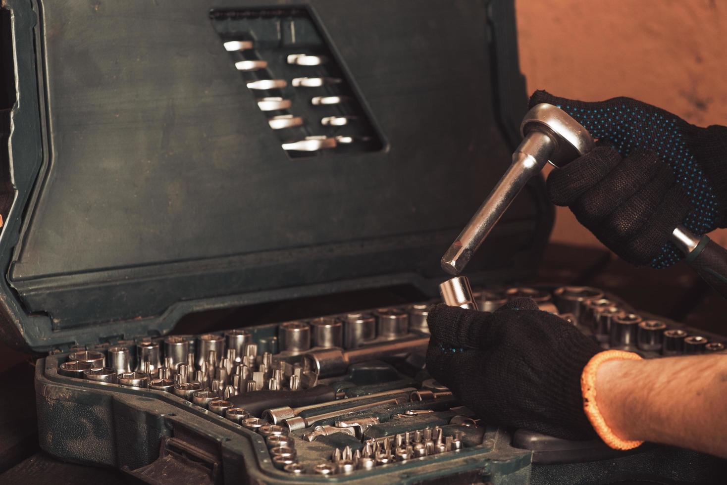 der automechaniker hält in der hand einen schraubenschlüssel und passagen auf dem hintergrund einer tafel mit werkzeugen zur reparatur des autos foto