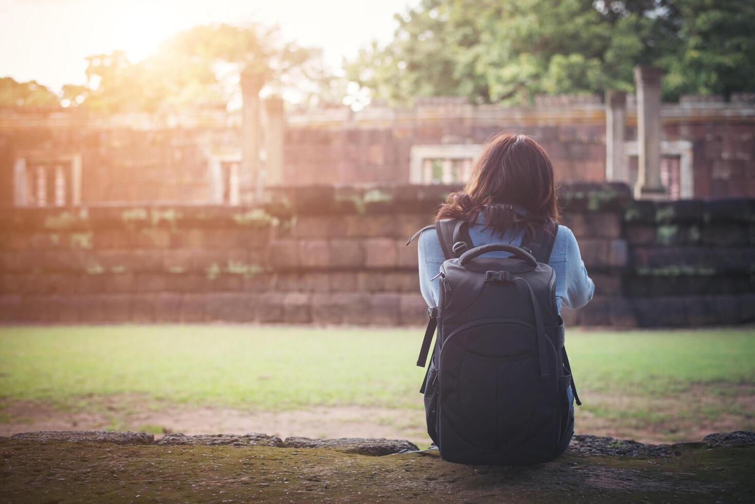 junge attraktive fotografin touristin mit rucksack, die kommt, um ein foto im alten phanom-sprossentempel in thailand zu schießen.