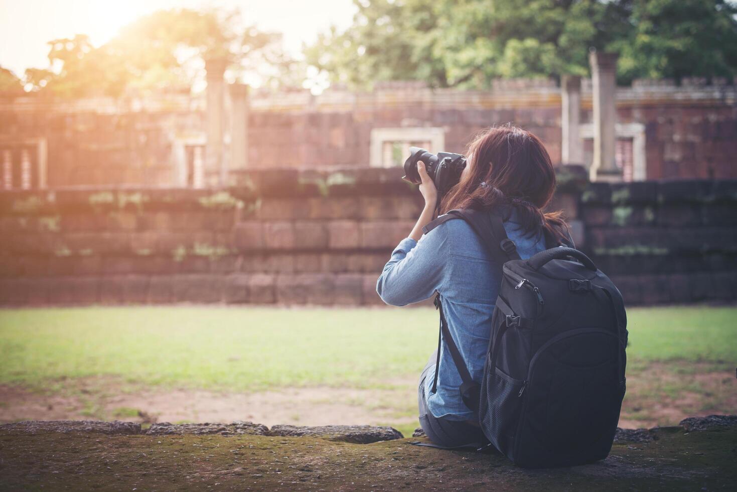 junge attraktive fotografin touristin mit rucksack, die kommt, um ein foto im alten phanom-sprossentempel in thailand zu schießen.