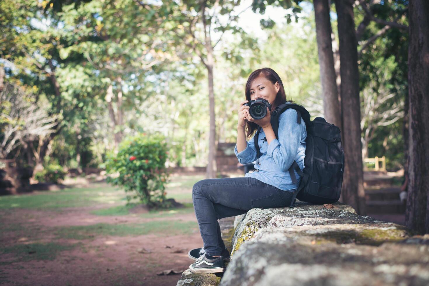 junge attraktive fotografin touristin mit rucksack, die kommt, um ein foto im alten phanom-sprossentempel in thailand zu schießen.