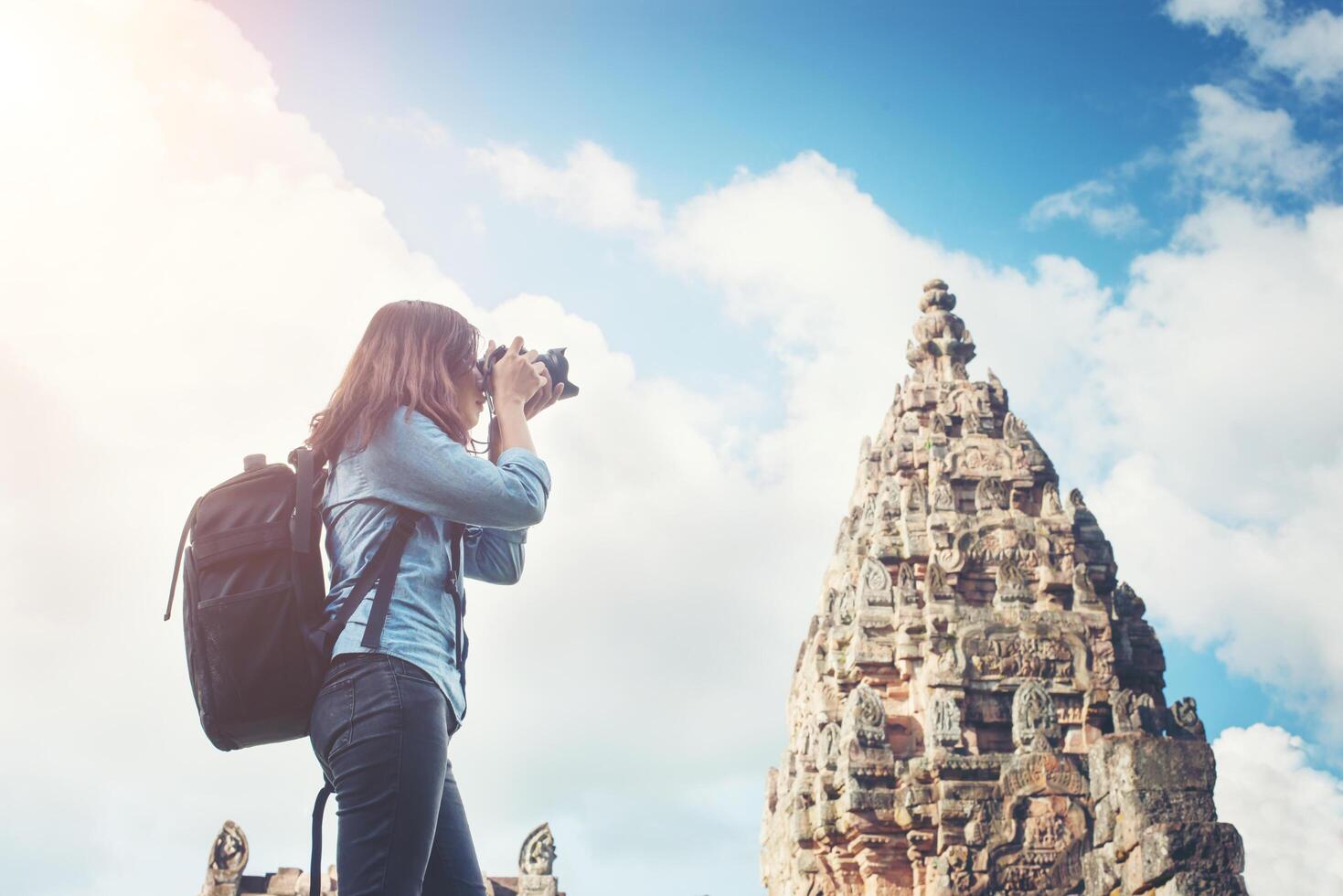 junge attraktive fotografin touristin mit rucksack, die kommt, um ein foto im alten phanom-sprossentempel in thailand zu schießen.