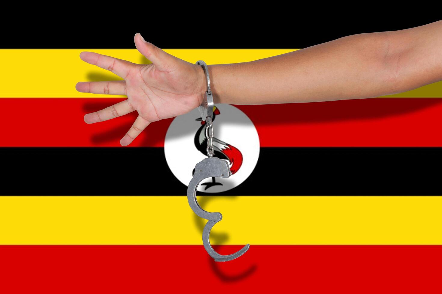 Handschellen mit Hand auf Uganda-Flagge foto