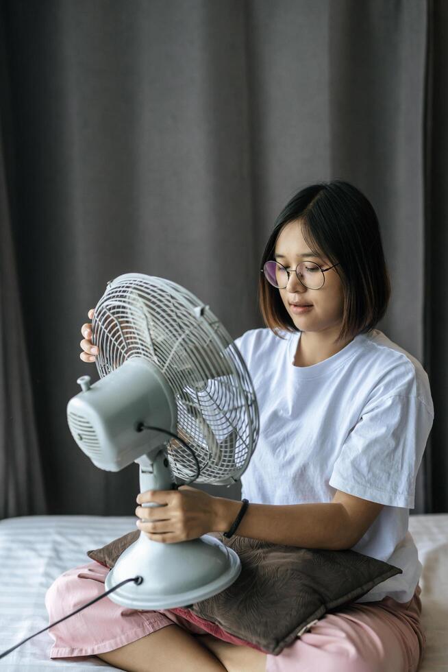 Frau, die ein weißes Hemd und einen Griff zum Ventilator trägt. foto