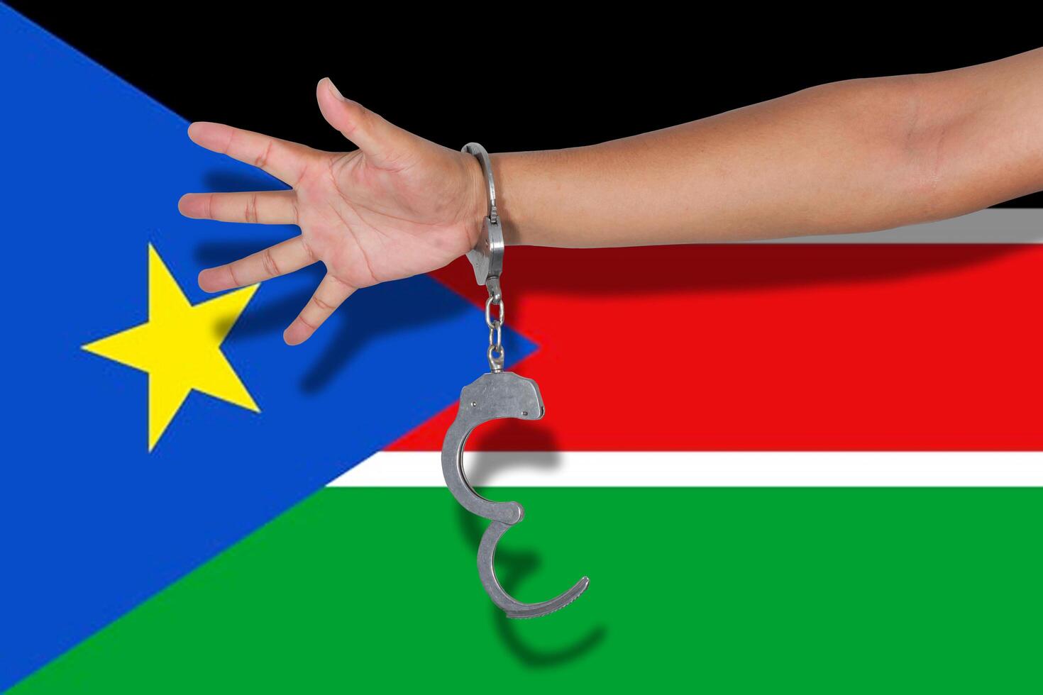 handschellen mit der hand auf der südsudan-flagge foto