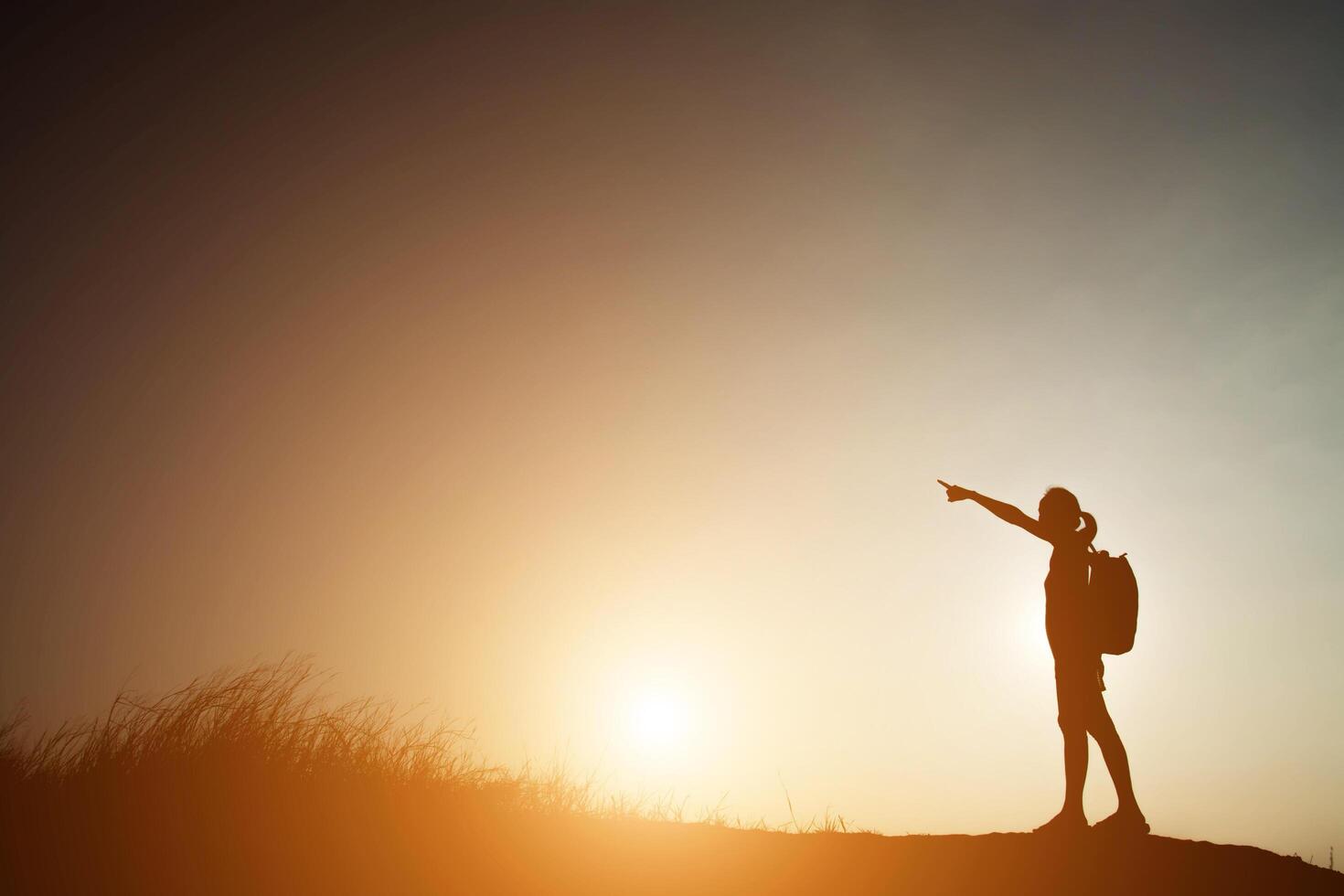 Silhouette einer Frau, die mit Sonnenuntergang wandert. foto