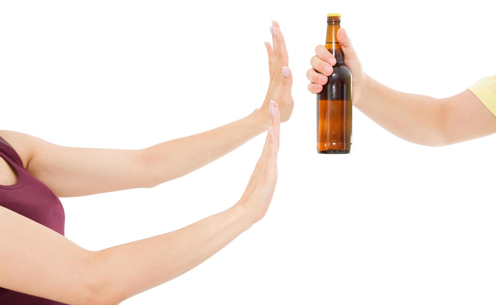 Weibliche Hand lehnt eine Flasche Bier ab, die auf weißem Hintergrund isoliert ist, Anti-Alkohol-Konzept. Platz kopieren, Vorlage, foto
