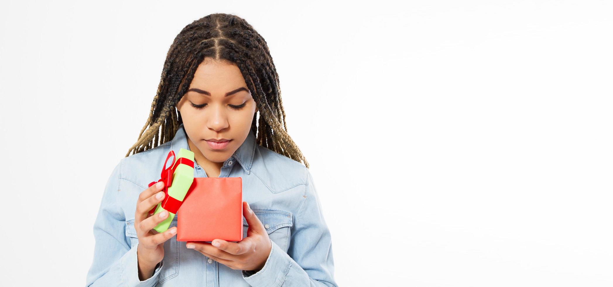Schönes afroamerikanisches Mädchen öffnet ein Geschenkbox-Kopierraum-Mock-up, Feiertagsfeierkonzept foto
