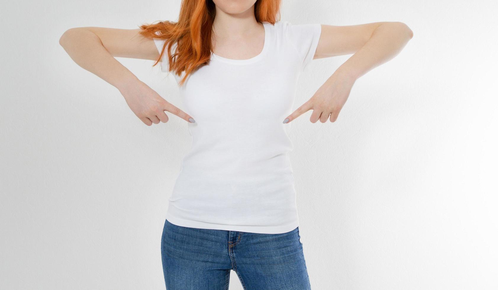 weißes T-Shirt auf einem Mädchen mit perfektem Körperbild. Frau, die auf T-Shirt zeigt. foto