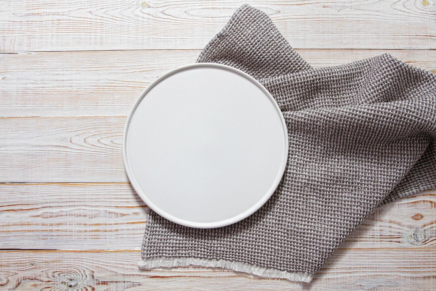 leere weiße Platte mit Serviette auf weißem Holztisch foto