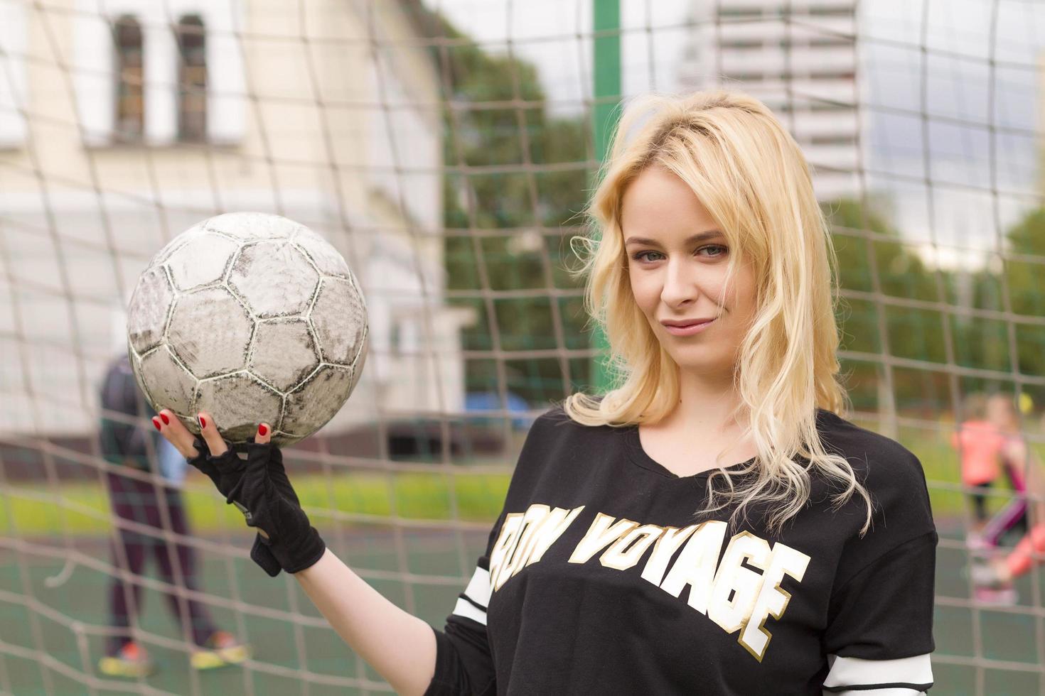 schöne Blondine mit einem Ball am Fußballtor. foto