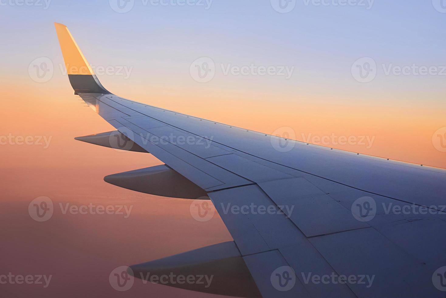 blick auf den flügel des flugzeugs am himmel während des sonnenuntergangs. Reise- und Transportkonzept foto