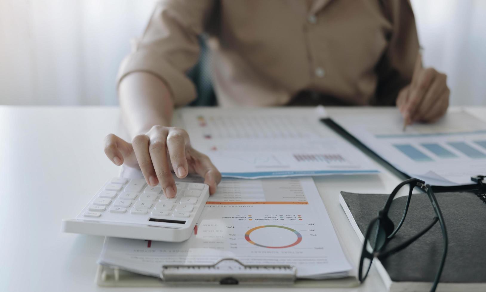 Nahaufnahme der Geschäftsfrau mit Taschenrechner und Laptop für mathematische Finanzen auf Holzschreibtisch im Büro- und Geschäftshintergrund, Steuern, Buchhaltung, Statistik und analytisches Forschungskonzept foto