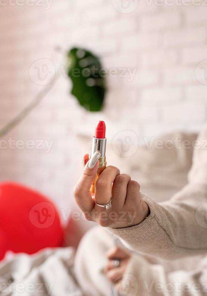 Frauenhand, die roten Lippenstift hält foto