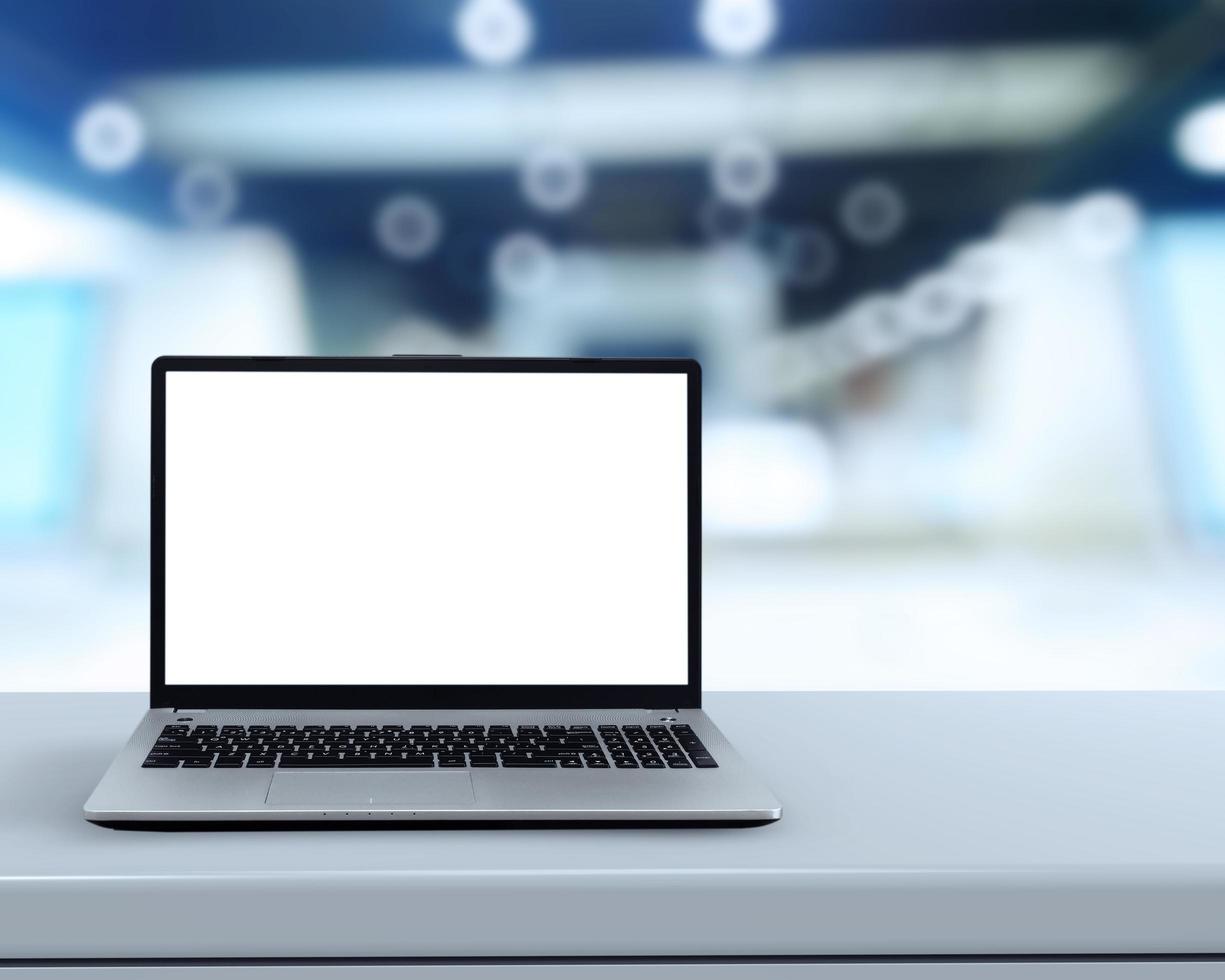 Laptop mit leerem Bildschirm auf weißem Schreibtisch mit unscharfem Hintergrund als Konzept foto