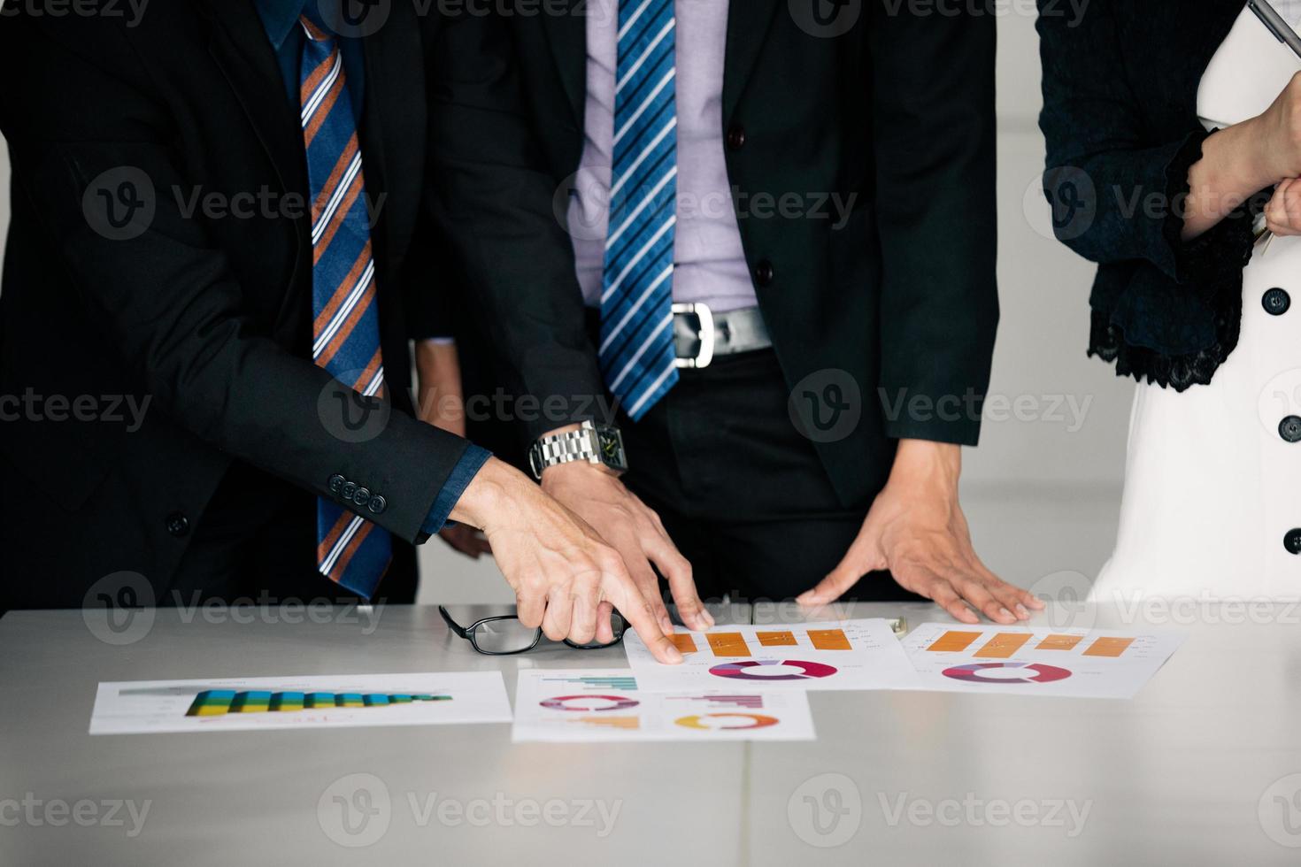 Geschäftsleute, die arbeiten und auf grafische Finanzdiagramme und Analysedokumente auf dem Bürotisch zeigen foto
