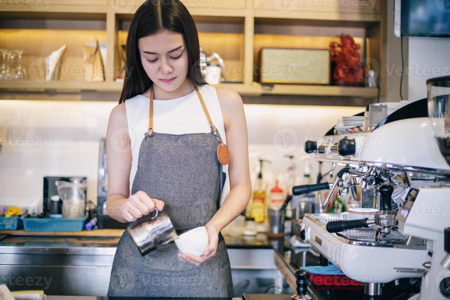 Asiatische Frauen Barista lächelnd und mit Kaffeemaschine in der Cafétheke - berufstätige Frau Kleinunternehmerin Essen und Trinken Café-Konzept foto