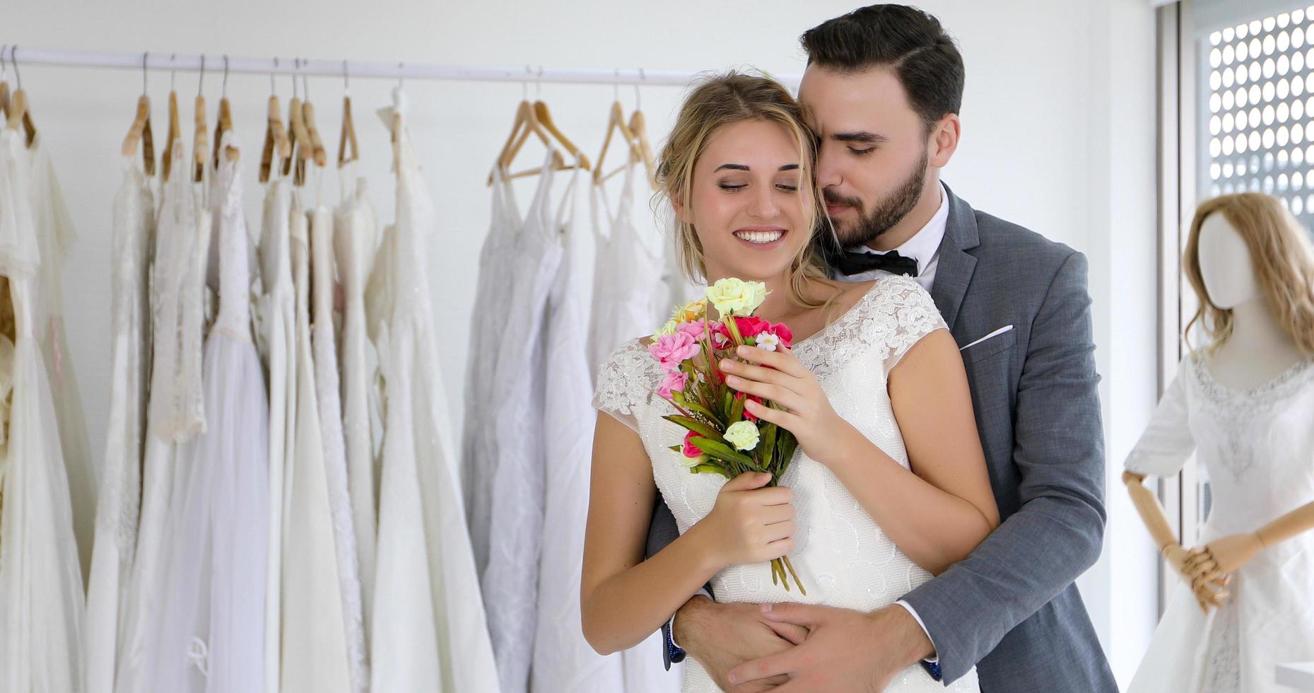 die liebhaber geben der braut blumen und küssen sich glücklich und paar lieben es, im hochzeitsstudio zu stehen foto