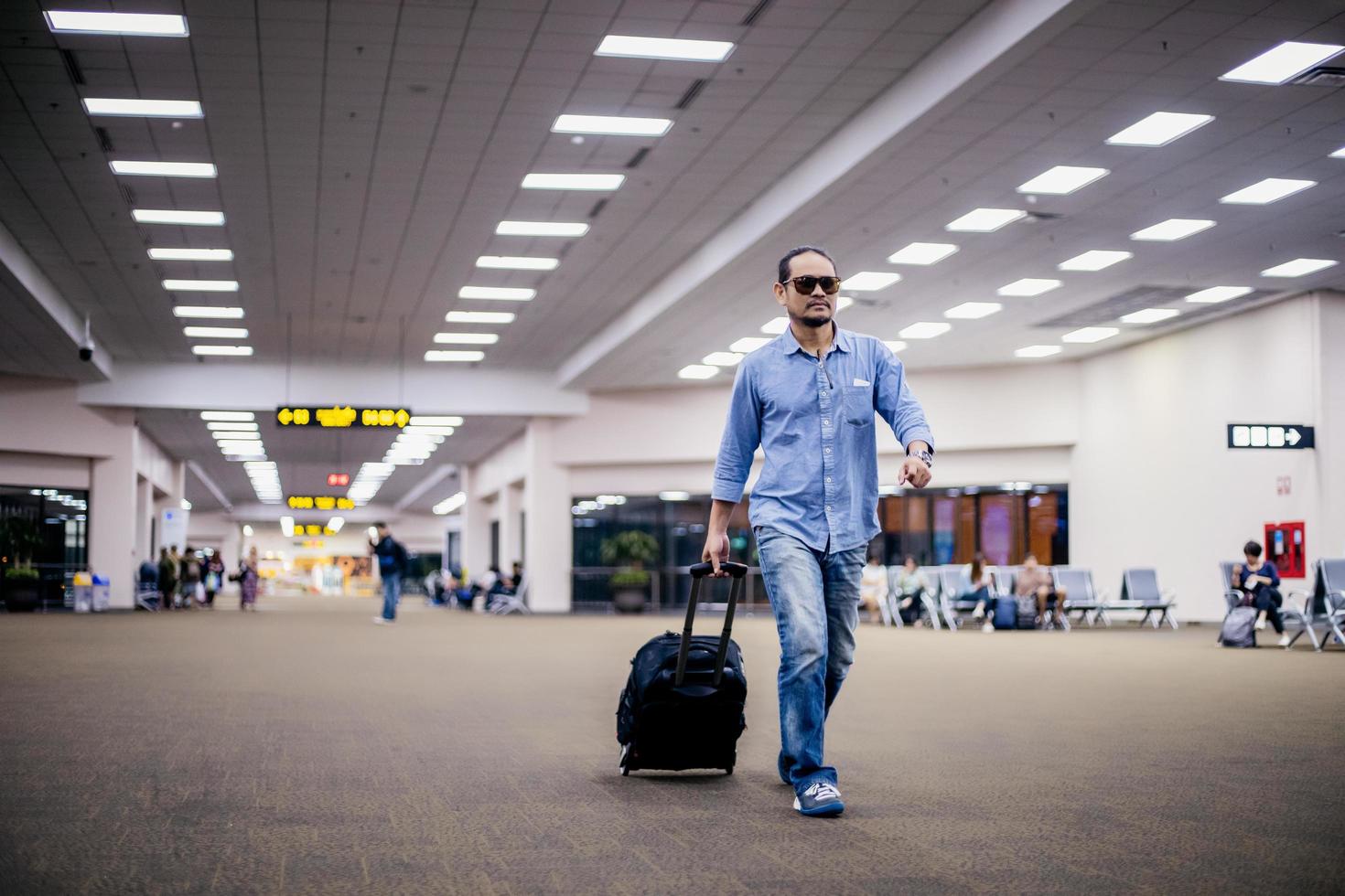 asiatischer Reisender mit Koffern zu Fuß und Transport auf einem Flughafen foto